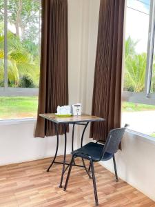 a table and a chair in front of a window at My Heaven Resort in Trang