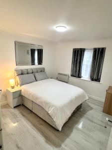 1 dormitorio con 1 cama blanca grande y 2 ventanas en RoyalLodge en Londres