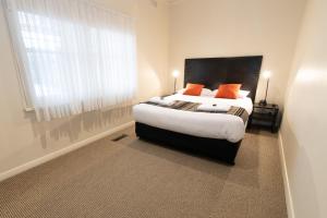 a bedroom with a bed with orange pillows and a window at Sovereign Park Motor Inn in Ballarat