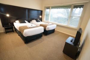 a hotel room with two beds and a television at Sovereign Park Motor Inn in Ballarat