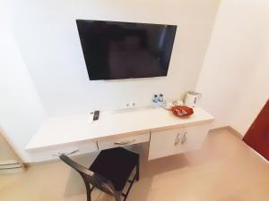 a white desk with a television on a wall at De Loran Hotel in Banjar