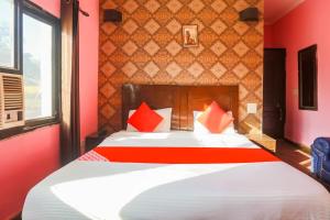 um quarto com uma cama grande e almofadas vermelhas em Super Collection O 1064 Tipsyy Inn Suites 17 em Sohna