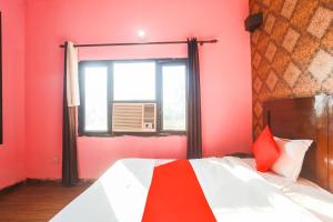Schlafzimmer mit roten Wänden und einem Bett mit Fenster in der Unterkunft Super Collection O 1064 Tipsyy Inn Suites 17 in Sohna