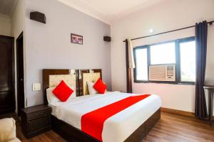 1 dormitorio con 1 cama grande con almohadas rojas en Super Collection O 1064 Tipsyy Inn Suites 17, en Sohna
