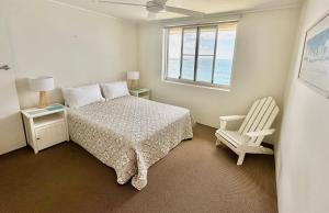 a bedroom with a bed and a chair and a window at Craigmore Penthouse in Yamba