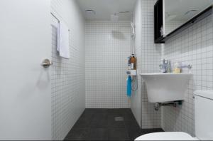 a white tiled bathroom with a sink and a toilet at Jois House in Jeju +21 photos