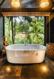 a bath tub in a room with a large window at Namu Garden Hotel & Spa in Puerto Viejo