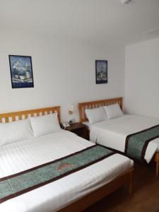 two beds in a room with white walls at Simon Hotel in Nha Trang