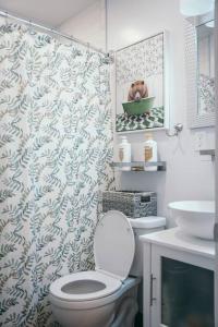 y baño con aseo y cortina de ducha. en Sleek and Cozy Micro Fells Point Residence! en Baltimore