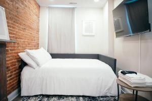 1 dormitorio con cama blanca y pared de ladrillo en Sleek and Cozy Micro Fells Point Residence! en Baltimore