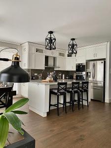 a kitchen with white cabinets and black bar stools at Luxury Apartment in Rzeszów