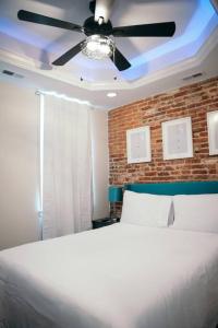a bedroom with a white bed with a ceiling fan at Sleek and Cozy Micro Fells Point Residence! in Baltimore