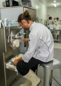 um homem numa cozinha a preparar comida numa máquina em Bodalla Dairy Shed Guest Rooms em Bodalla