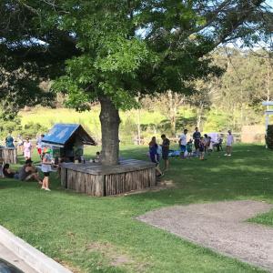 un grupo de personas de pie alrededor de un árbol en un parque en Bodalla Dairy Shed Guest Rooms, en Bodalla