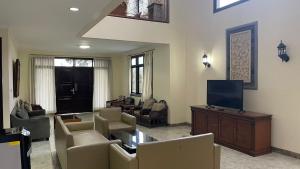 un soggiorno con divano, TV e sedie di Green Hill Resort Kemuning a Panyaweuyan