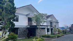 une maison blanche avec un mur en briques dans l'établissement Green Hill Resort Kemuning, à Panyaweuyan