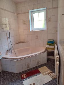 ein Bad mit einer Badewanne und einem Fenster in der Unterkunft Ferienhaus Schöller in Schönbach