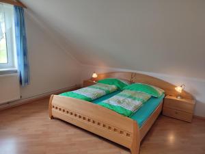 1 dormitorio con 1 cama con sábanas verdes y 2 lámparas en Ferienhaus Schöller, en Schönbach