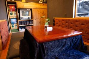 Zimmer mit einem Holztisch und einem TV in der Unterkunft AKIYA nehemiah - Vacation STAY 84870 in Awaji