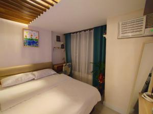 a bedroom with a white bed and a window at Your Desire Staycation in Manila