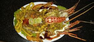 un plato de comida con camarones y verduras en una mesa en Giman Free Beach Resort, en Pasikuda