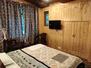 a bedroom with a bed and a tv in a room at Dream River Guest House in Pahalgām