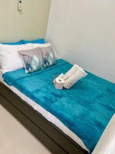 a bed with a blue blanket and two pillows at 1 BR South Residences SM Southmall Netflix / Alexa in Manila