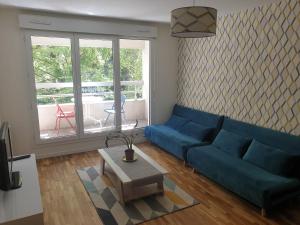 ein Wohnzimmer mit einem blauen Sofa und einem Tisch in der Unterkunft ''Le Verlaine'' T2 au cœur de l'agglomération Lyonnaise in Villeurbanne + 5 Fotos