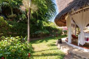 a garden with a palm tree and a house at Minimi Couzy villa casaurina in Malindi