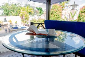 a glass table with a book and a cup of coffee at Tentram Homestay Jimbaran in Jimbaran