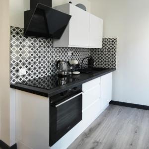 una cocina con armarios blancos y encimeras negras en Appartement au centre ville en Lourdes