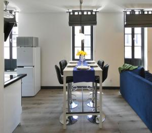 cocina con mesa con sillas y sofá azul en Appartement au centre ville en Lourdes