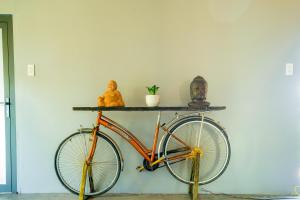 ein orangefarbenes Fahrrad neben einer Wand mit einer Statue in der Unterkunft Ann Village in Cái Răng