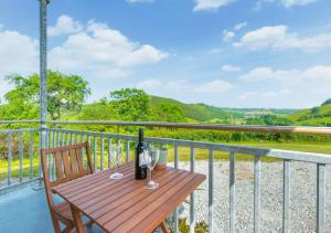 a wooden table with a bottle of wine on a balcony at Cwmachau - Tynant in Lower Chapel