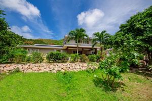 a house with palm trees and a stone wall at Anse Boudin Chalets & Villa in Anse Possession