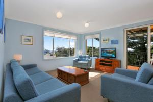 a living room with two blue couches and a tv at Aquarius Apartment 7 in Hawks Nest