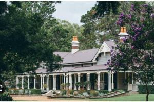 a large white house with a porch and trees at Inner City Studio 501 in Toowoomba