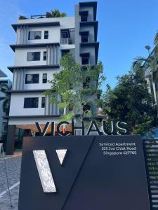 VicHaus Serviced Apartment في سنغافورة: مبنى أبيض طويل مع علامة أمامه