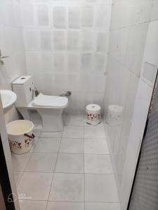 a white bathroom with a toilet and a sink at Apna Guest House Dehradun in Dehradun