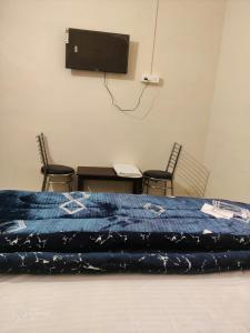 una camera con letto, tavolo e TV di Apna Guest House Dehradun a Dehradun