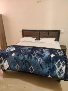 uma cama com uma colcha azul e branca em Apna Guest House Dehradun em Dehradun