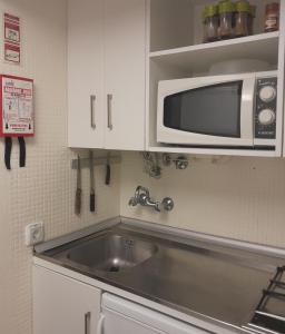 a kitchen with a sink and a microwave at Small apartment by the beach in Sesimbra