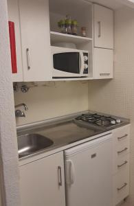 a small kitchen with a sink and a microwave at Small apartment by the beach in Sesimbra