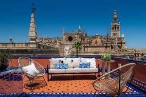 a couch and two chairs on a balcony with a building at Magno Apartments Santo Tomas in Seville