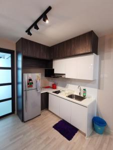 a kitchen with white cabinets and a stainless steel refrigerator at H20 Residence Ara Damansara Petaling Jaya in Petaling Jaya