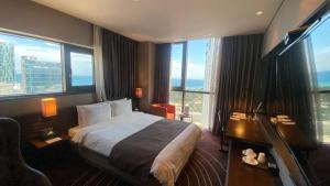 um quarto de hotel com uma cama e janelas grandes em Best Louis Hamilton Hotel Haeundae em Busan