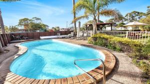 a swimming pool with a wooden deck around it at unit 6 53 Ocean Drive, Merimbula in Merimbula