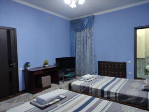 Cette chambre bleue comprend deux lits et un bureau. dans l'établissement REAL Tashkent, à Tachkent