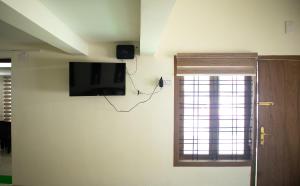 a room with a tv on the wall and a window at Salalah Enclave - 3 AC Bedroom House at Vytilla, Kochi in Cochin