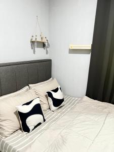 ein Bett mit zwei schwarzen und weißen Kissen darauf in der Unterkunft Modern Style Village House in Kuching